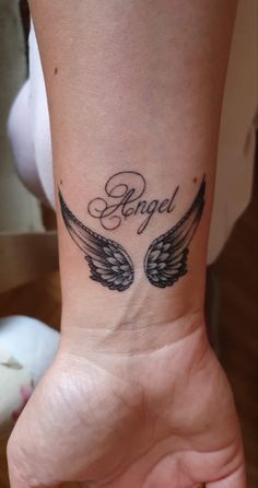 an angel wrist tattoo with the word angel on it and two wings in black ink