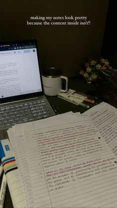 a laptop computer sitting on top of a desk next to a pile of books and papers