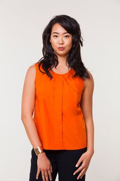 a woman in an orange top is posing for the camera with her hands on her hips