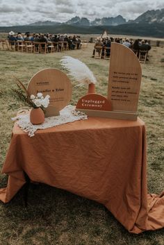 a table topped with two vases sitting on top of a grass covered field next to a wooden sign