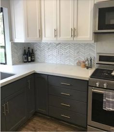 a kitchen with gray cabinets and white counter tops is pictured in this image, there are two bottles on the stove