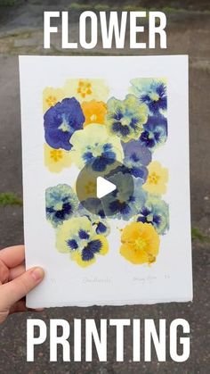 a person holding up a piece of paper with flowers painted on it and the words, flower printing