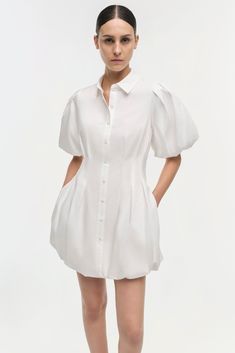 SIGNATURE COLLECTION Our Signature Cleo Mini Dress in White. The everyday ease of cotton poplin, crafted into a pleated mini dress with ballooned sleeves and a slimming, pintucked waist. A Simkhai signature. Daywear Dresses With Blouson Sleeves, Mini Length, Mini Dress With Blouson Sleeves For Daywear, Spring Dresses With Blouson Short Sleeves, White Puff Sleeve Dress With Pleated Sleeves For Daywear, Feminine Pleated Sleeves Mini Dress For Summer, Feminine Summer Mini Dress With Pleated Sleeves, Chic Mini Dress With Lantern Sleeves For Daywear, White Voluminous Puff Sleeve Dress For Spring, Voluminous White Puff Sleeve Dress For Spring