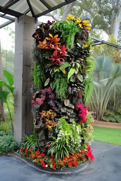 a very tall planter filled with lots of different types of flowers and plants in it