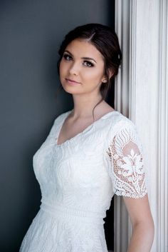 a woman in a white dress leaning against a wall