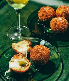 some food is sitting on a glass plate next to a wine glass and another drink