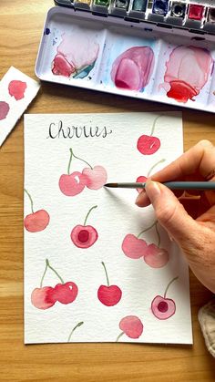 someone is painting cherries with watercolors on paper