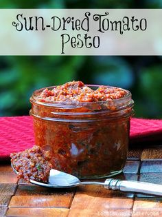 sun dried tomato pesto in a glass jar with spoon on the table next to it