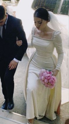 a man in a suit and tie walking next to a woman in a wedding dress