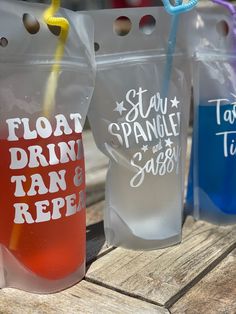 three plastic bags with straws in them sitting on a wooden table next to each other