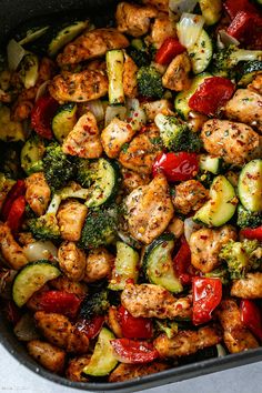 a pan filled with chicken, broccoli and peppers