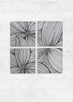 three black and white artwork pieces on a concrete wall, each with an abstract flower design