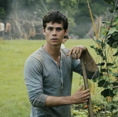 a young man holding a stick in the grass