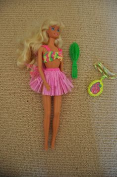 a barbie doll is laying on the floor next to a hairbrush