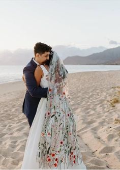 a bride and groom embracing on the beach