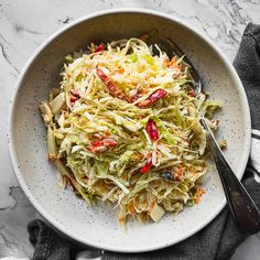 a white bowl filled with coleslaw salad on top of a marble countertop