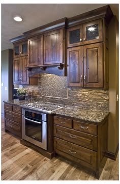 a kitchen with wooden cabinets and granite counter tops in the center, along with stainless steel appliances