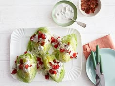 lettuce wrapped in cheese and tomatoes on a white plate next to a bowl of ranch dressing