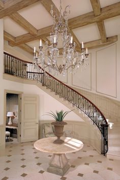 a chandelier hangs from the ceiling above a table with a potted plant on it