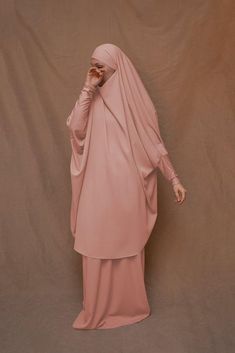 Introducing Pink Moira Prayer Umrah Gown with Niqab Feature from Annah Hariri. This beautiful gown is made from high-quality Nada abaya fabric and features super light, stretchy jersey sleeves for ultimate comfort. The elasticated waistband and full skirt ensure a flattering and secure fit, while the khimar can be tied at the back of the head for added coverage.But the best part? This gown can also be transformed into a niqaab with just a few simple stitches. So whether you're performing Umrah, Long Niqab With Dabka For Eid, Long Dabka Niqab For Eid, Modest Wedding Niqab For Eid, Modest Style Khimar For Wedding And Eid, Long Khimar For Wedding Eid Festival, Long Khimar For Wedding, Long Khimar For Wedding And Eid, Floor-length Wedding Khimar With Dabka, Wedding Floor-length Dabka Khimar