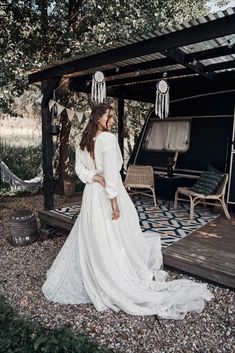 a woman in a white wedding dress standing on the ground next to an outdoor gazebo