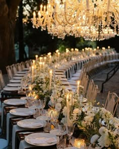 a long table is set up with white flowers and candles for an elegant wedding reception