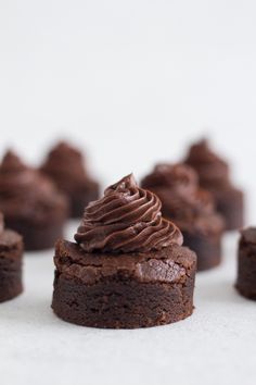 chocolate cupcakes with frosting sitting on top of each other in front of others