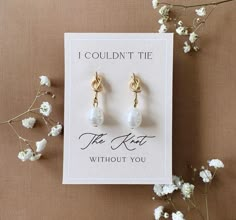 a pair of earrings sitting on top of a card next to some flowers and branches