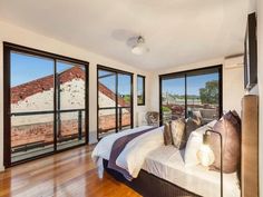 a bedroom with hardwood floors and large windows