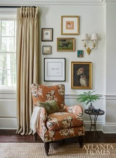 a living room with pictures on the wall and a chair in front of a window