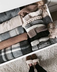 a drawer filled with sweaters and slippers on top of a carpeted floor