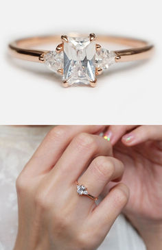 a woman's hand holding an engagement ring with three stones on it and the other side