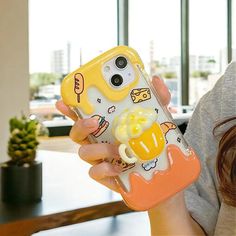 a woman holding a cell phone case with an image of a cartoon character on it