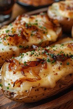 baked potatoes covered in cheese and herbs on a wooden cutting board with other food items