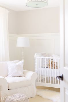 a baby's room with a crib and white furniture