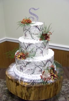 a three tiered wedding cake on top of a tree stump