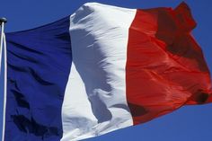 the flag of france is flying high in the sky