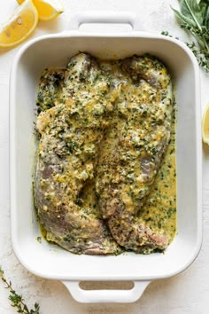 baked fish in a white casserole with herbs and lemons