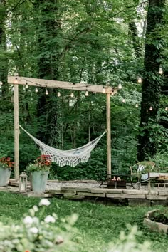 a hammock and some potted plants in a yard with lights hanging from the trees