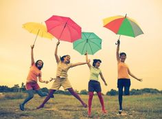 four people jumping in the air with umbrellas