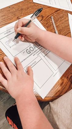 a person is doing something on top of a table with papers and pens in front of them