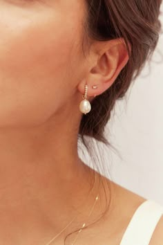 a woman wearing a pair of earrings with pearls on the end of her ear,