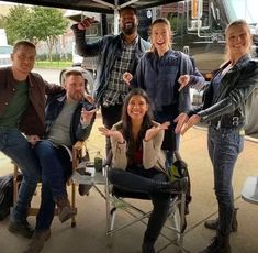 a group of people standing and sitting under a tent with their hands in the air