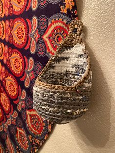 a woven basket hanging on the wall next to a colorful tapestry and decorative art piece