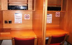 two wooden desks with red chairs next to each other in front of a microwave