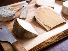 cheese is on a cutting board with a knife and some other food items around it