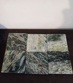 four different colors of marble tiles on a wooden floor