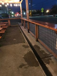 a wooden bench sitting on the side of a road next to a parking lot at night