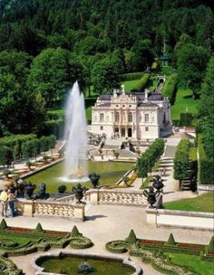 an aerial view of a mansion with a fountain in the foreground and gardens surrounding it