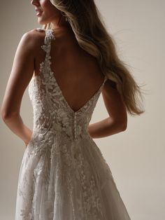 the back of a wedding dress with an open neckline and floral appliques